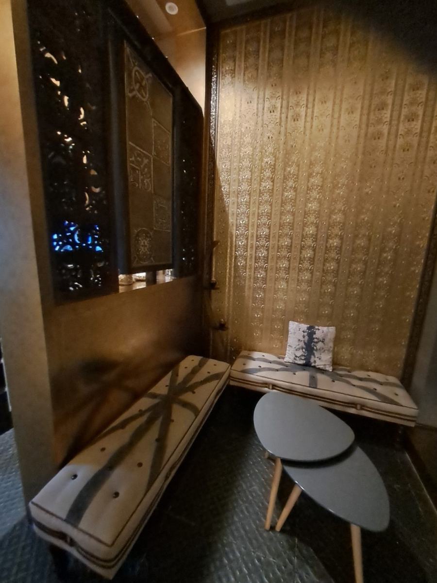 Waiting lounge with cushioned benches and a low table against a gold papered wall