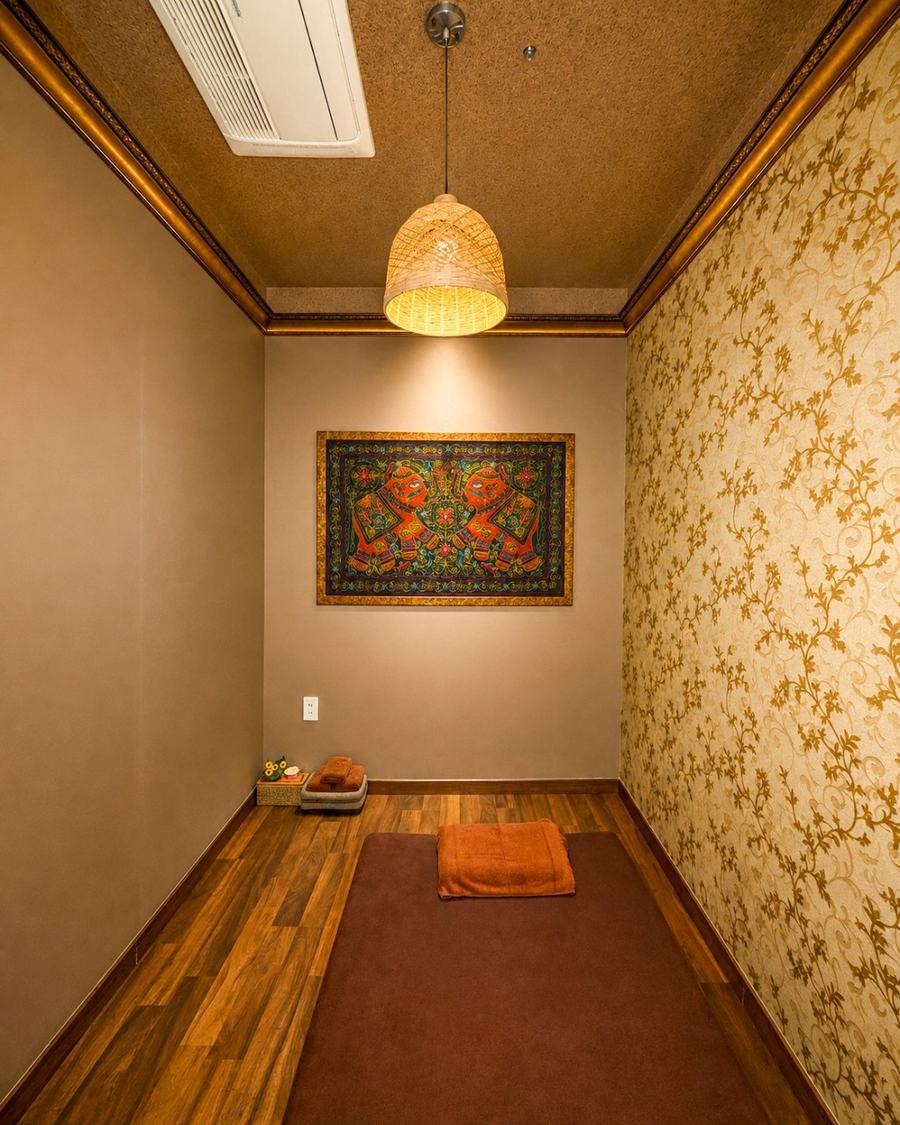 Private single treatment room with a floor mat, towels and a Thai textile panel