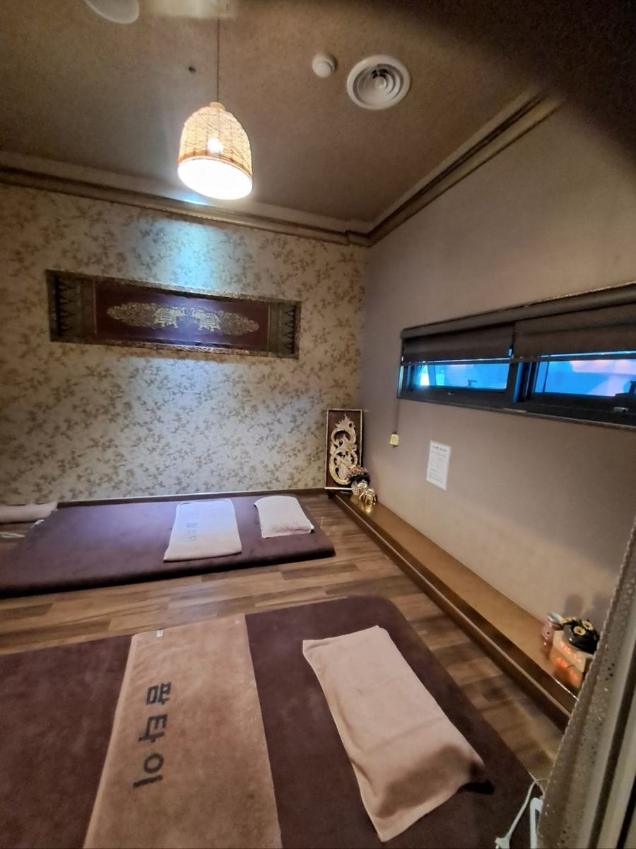 Treatment room with two floor mats, folded Palm Thai towels and a Thai wall panel
